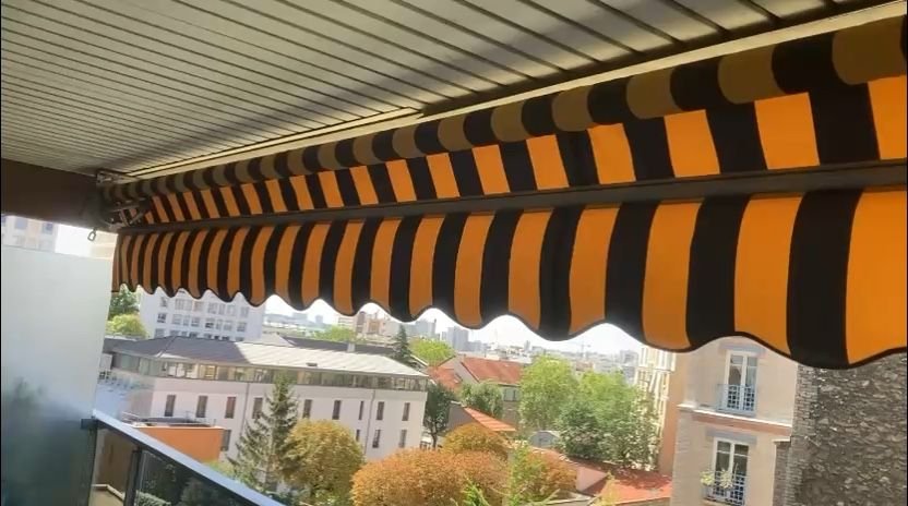 Store banne motorise deploye sur un balcon avec vue sur Paris